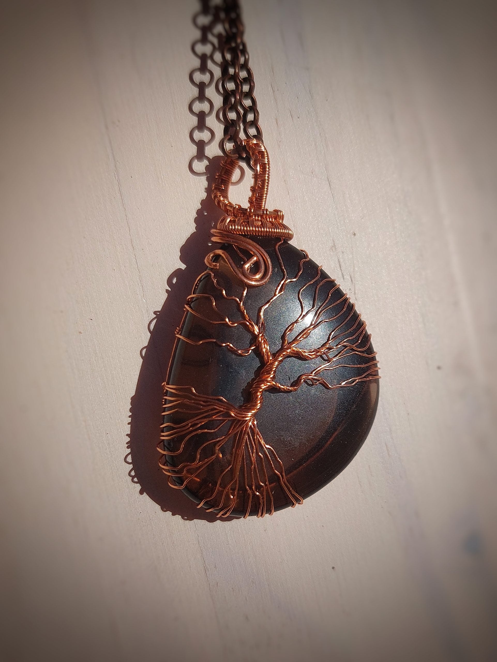 Smoky quartz Tree of Life pendant wrapped in copper wire hanging on chain