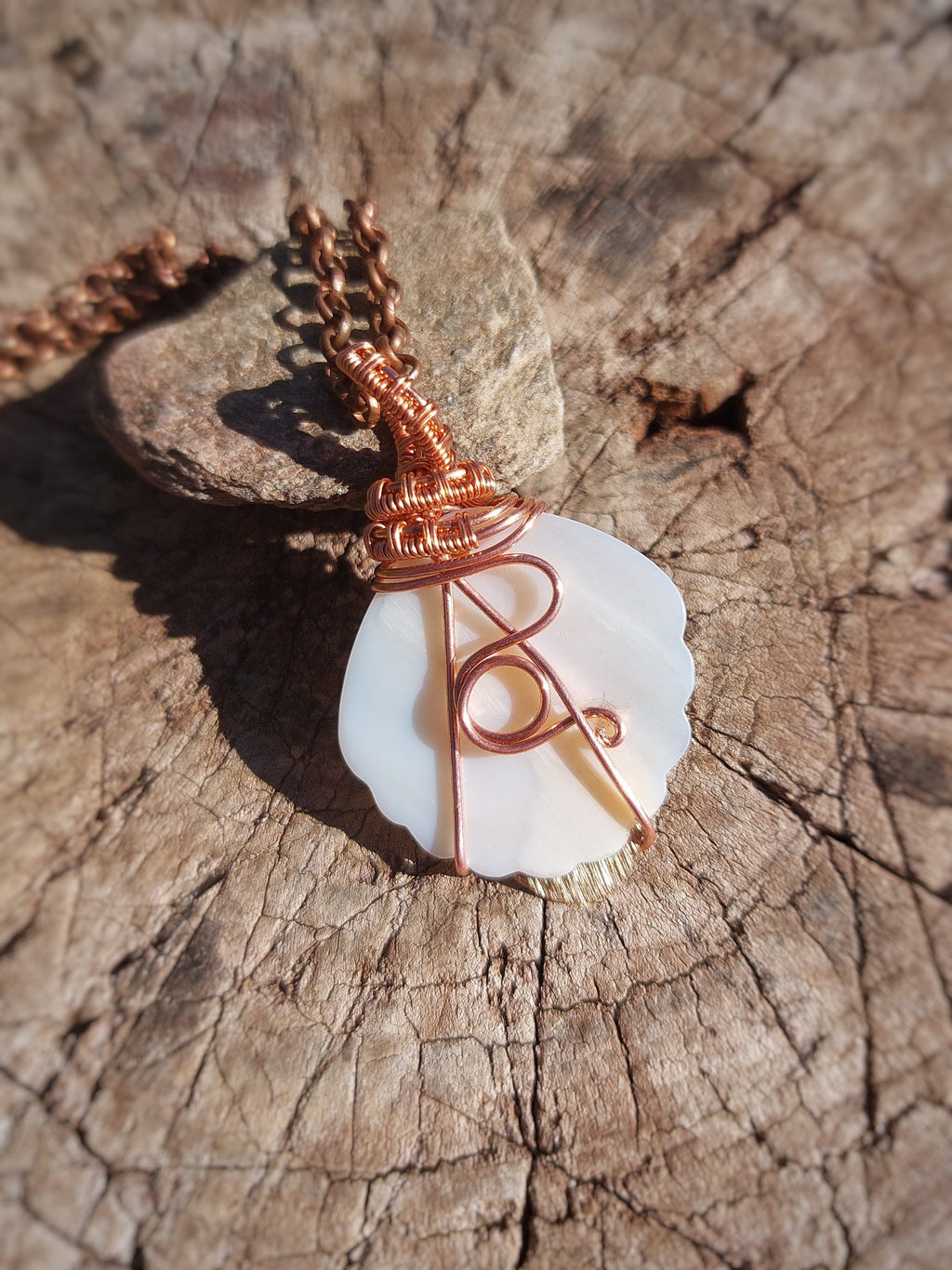 Close-up of mother of pearl copper and brass wire wrapped pendant hanging on chain