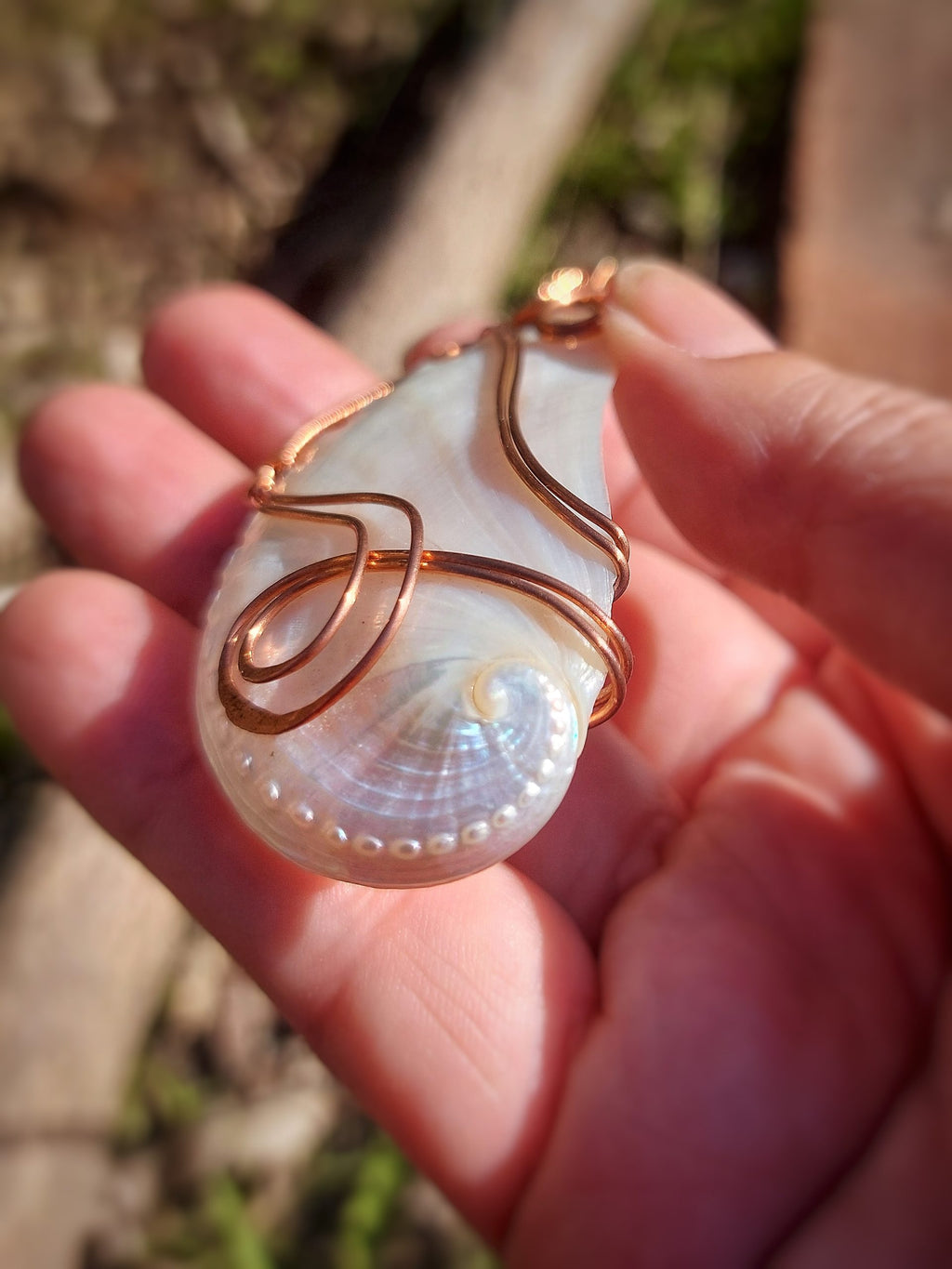 Close-up of mother of pearl guardian pendant in hand