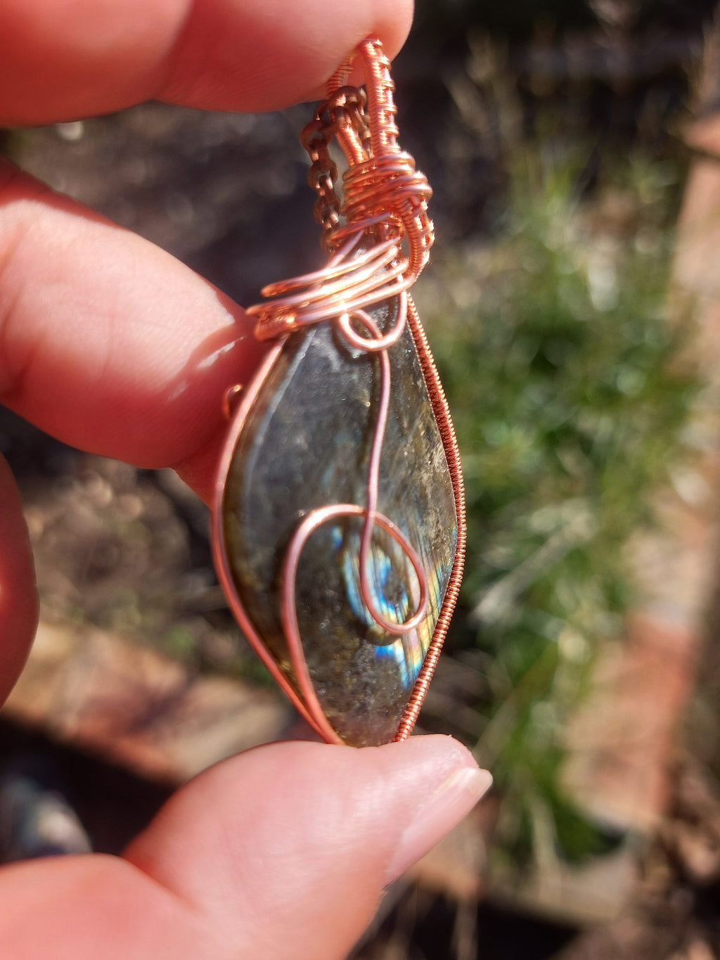 Close-up of labradorite crystal pendant with blue flash and copper wrapping