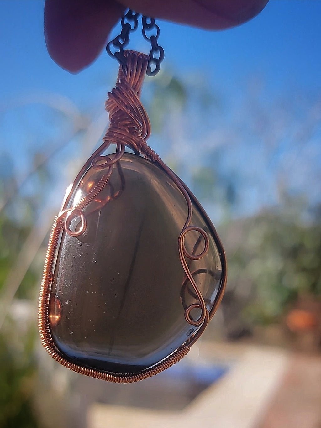 Smoky Quartz crystal pendant with dragon eye shape in natural daylight