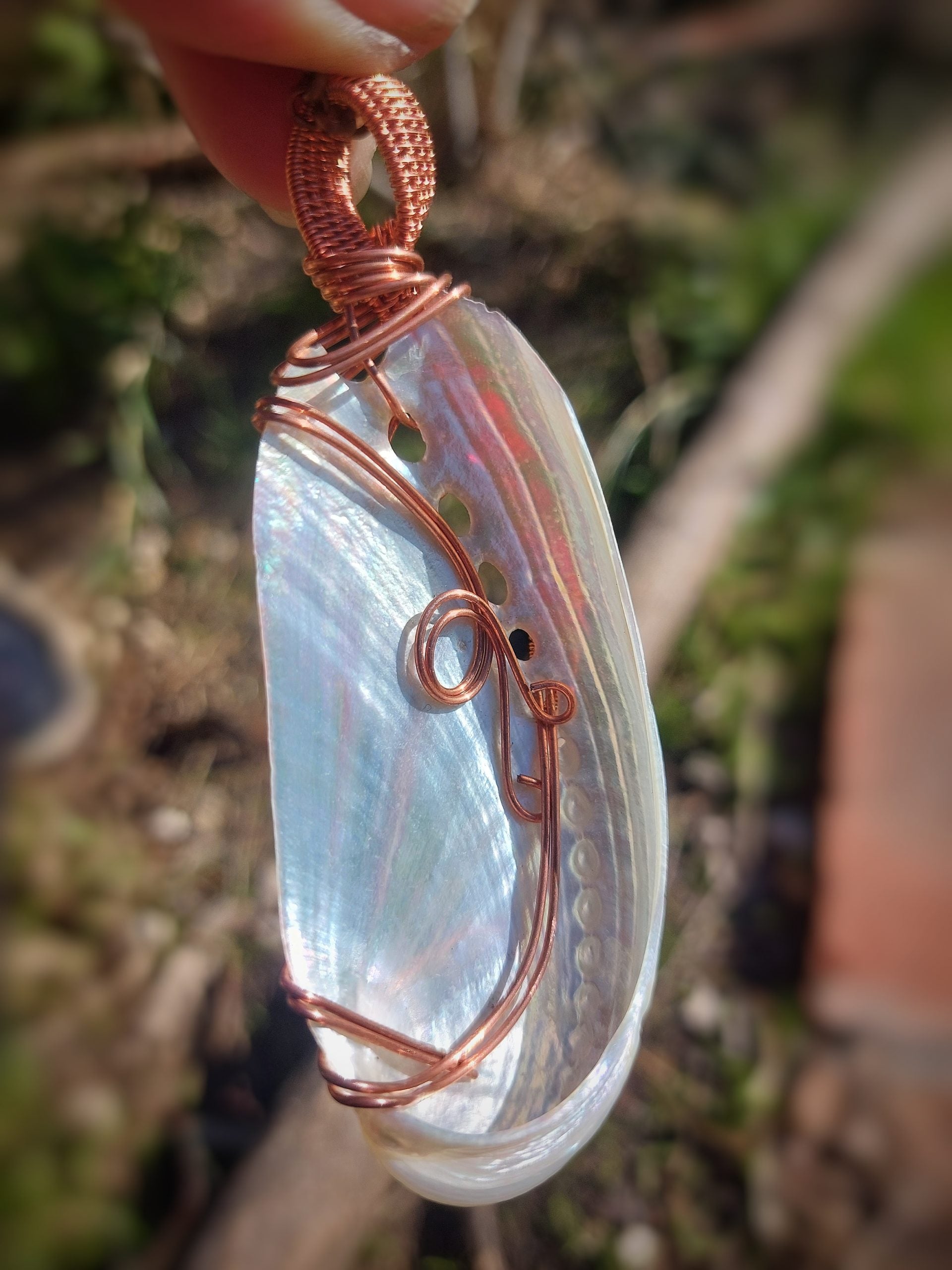 Side view of copper wire wrapped shell pendant