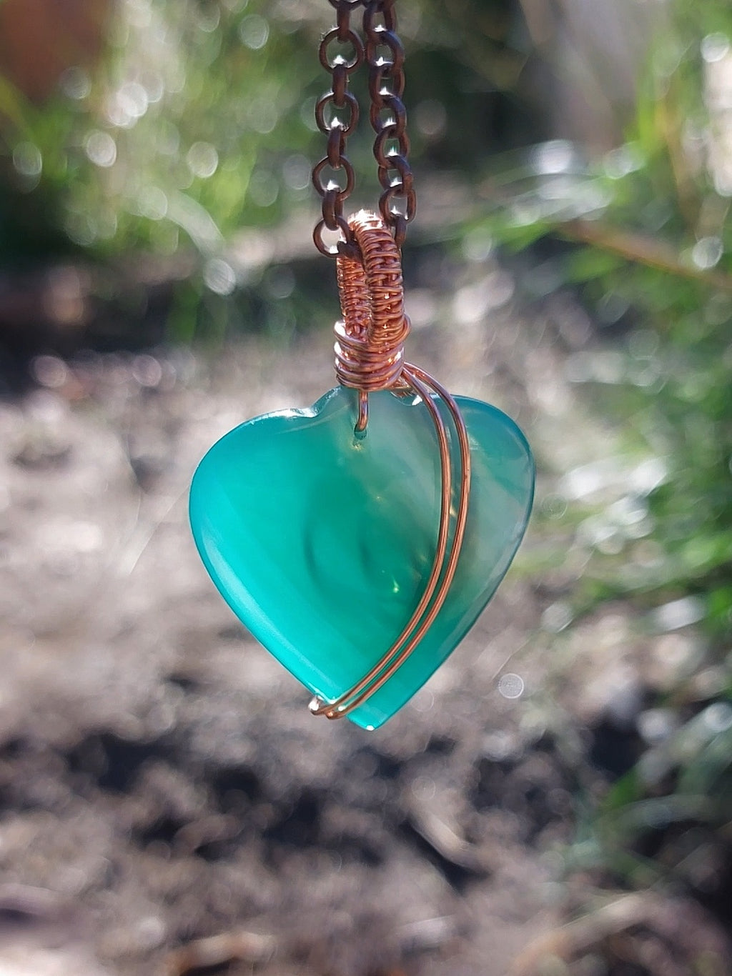 Green agate heart crystal necklace with copper wire wrapping close-up